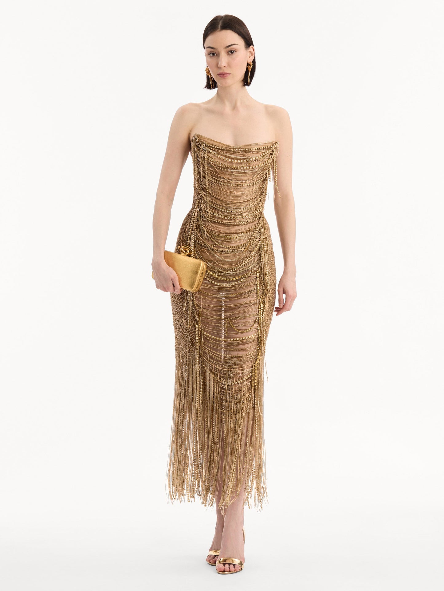 The model is wearing the Knot Minaudière in Gold. Full-Body View.
