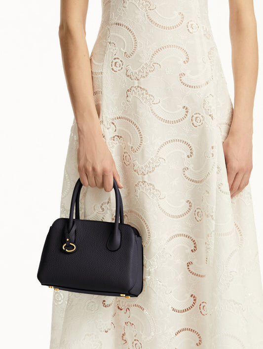 Mini Ivy in a light dark navy. The Mini Ivy is a top handle bag with a detachable shoulder strap, and it has the Oscar O logo attached around the top handle. Front View.