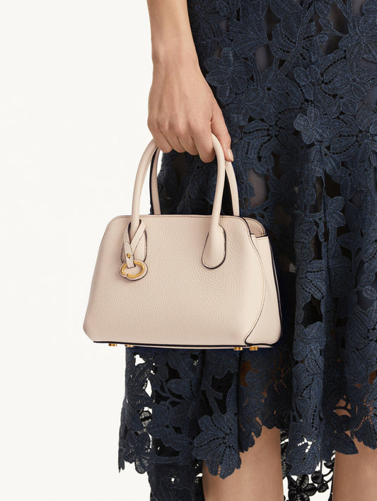 The Mini Ivy top handle handbag in Ivory. This bag comes with a detachable shoulder strap and has an Oscar O logo tag around the handle. Front View.