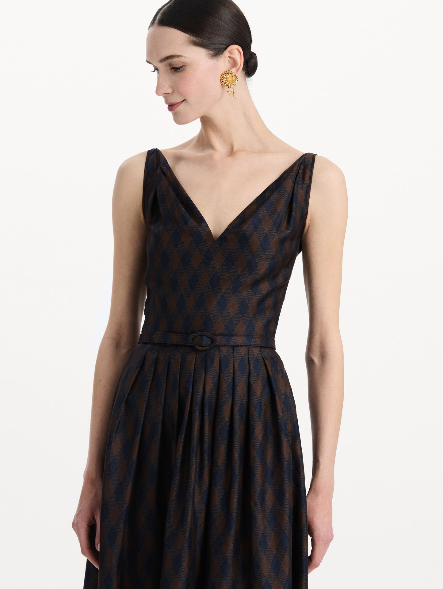The model is wearing the argyle silk twill dress with a sleeveless silhouette, a V-neckline, and an argyle print in navy and brown. Zoom view.