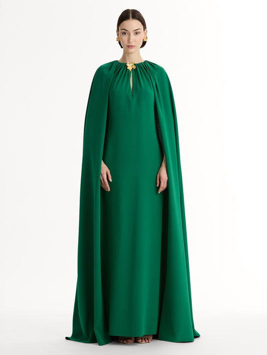 Emerald georgette caftan with fluid silhouette. Singular gilded cyclamen detail offers a sculptural focal point. Sweeping cape-like shape. Front View.