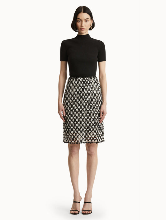 Full body front view of model wearing a high waisted black and ivory floral embroidered pencil skirt that follows a tweed pattern.