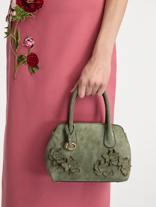 The Mini Ivy With Laser Cut Flowers in sage has a compartment with top handles and a removeable shoulder strap with various Oscar 'O' emblems on the hangtag and magnetic closure.