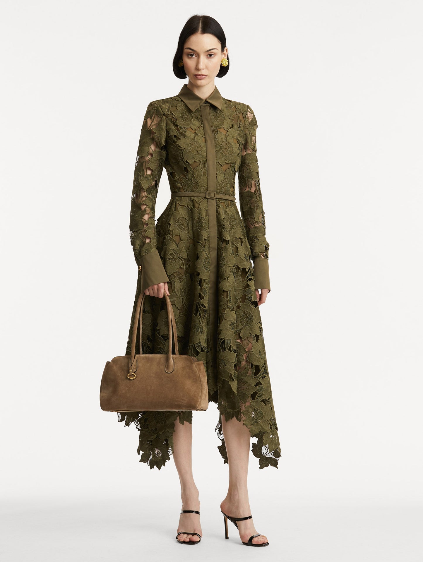 Full body model image of The Aster in taupe which features decisive lines and gently curved sides that mimic the Oscar 'O.' Elongated top handles and gold hardware and an emblem-stamped tag.