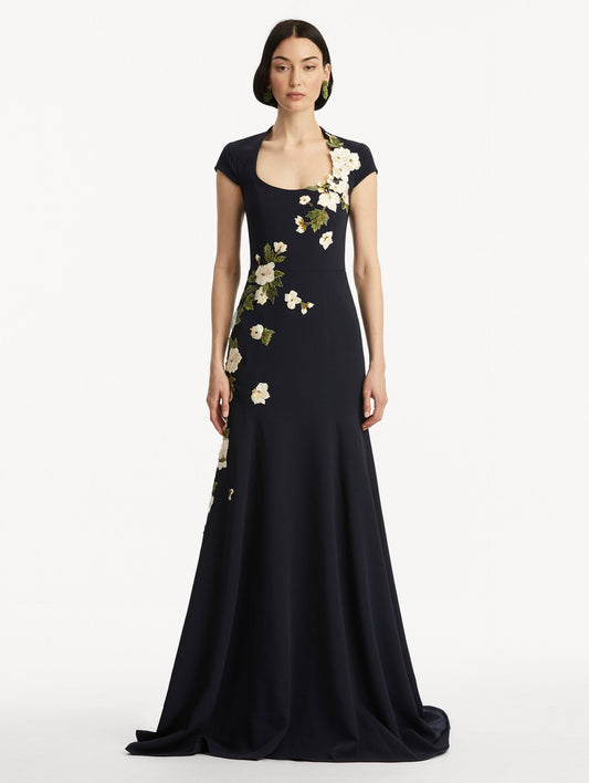Model wearing short sleeve navy gown with white cherry blossoms embroidered. Front view