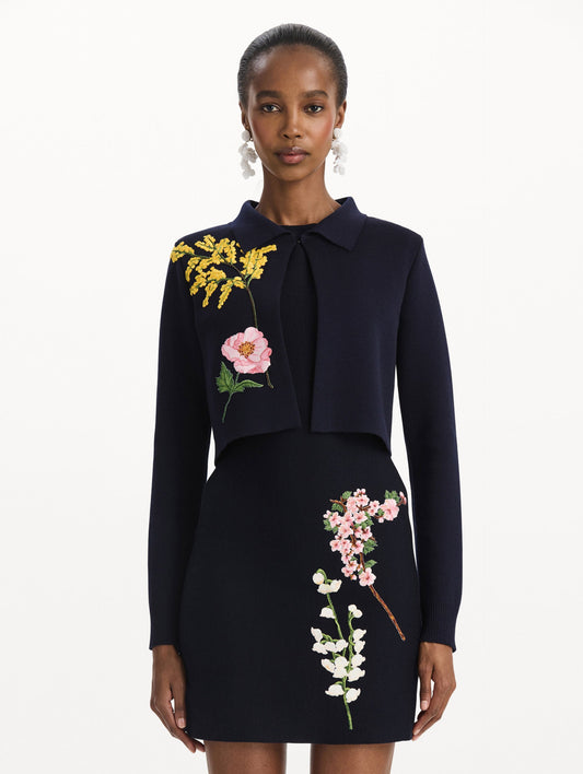 The model is wearing the mixed botanical cropped jacket with delicate embroidery in the color navy. Front view.