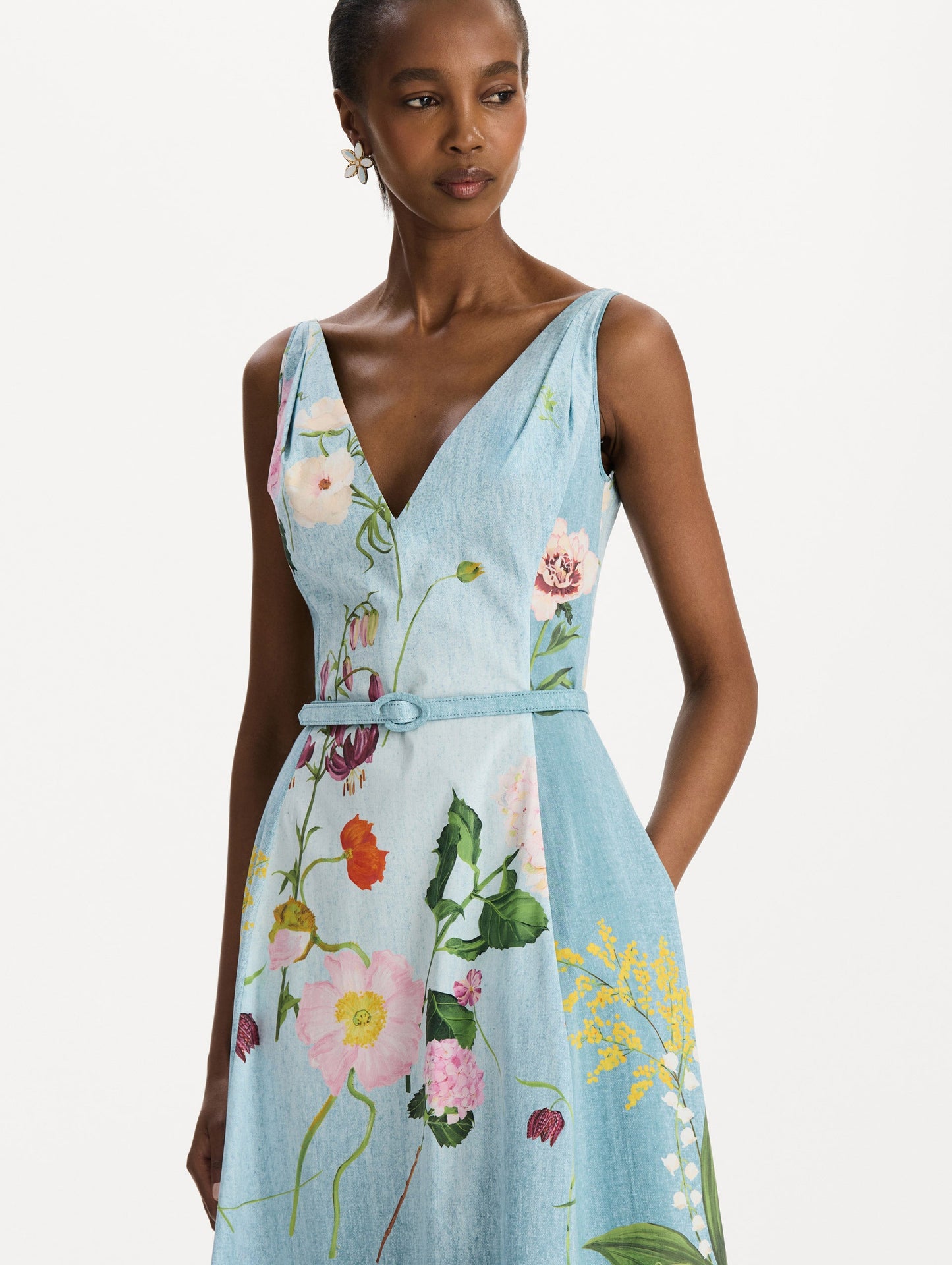 The model is wearing the mixed botanical cotton poplin dress with a sleeveless V-neck silhouette and an all-over floral print in blue multi. Zoom view.