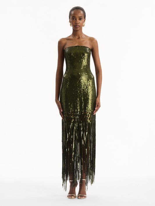 The model is wearing the Sequin Fringe Gown in green. Featuring a strapless neckline, fitted silhouette, and an open lattice detail cascading into a fringe skirt. Front View.