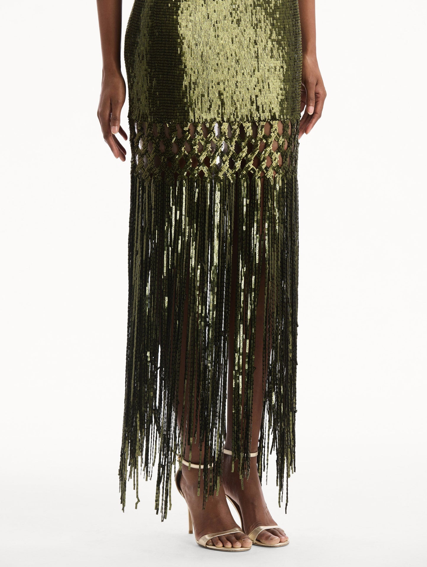 The model is wearing the Sequin Fringe Gown in green. Featuring a strapless neckline, fitted silhouette, and an open lattice detail cascading into a fringe skirt. Detail View.