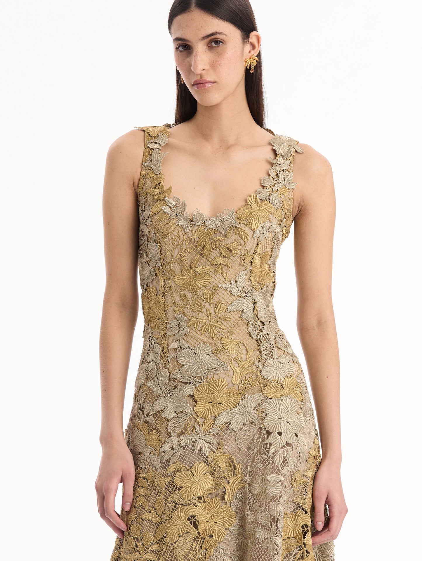 The model is wearing the Hibiscus Metallic Guipure Cocktail Dress in Gold. Featuring metallic guipure lace, a fitted bodice, and softly flared skirt. Detail View.