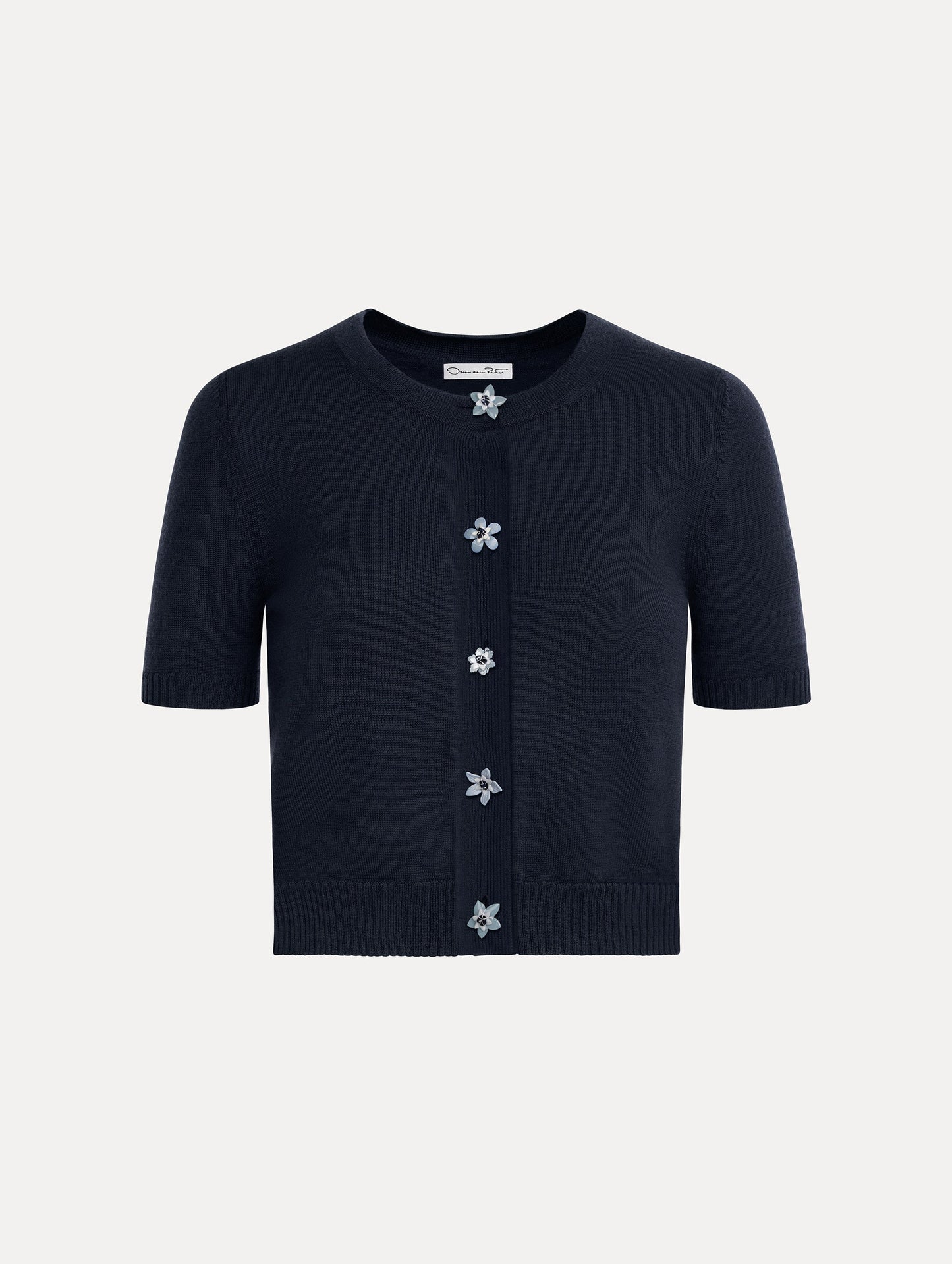 Cropped navy crew neck cardigan, short sleeves, floral buttons. Front View.