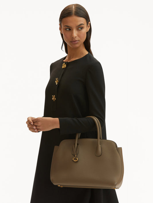 Model in black dress holding The Ivy leather bag in taupe. Front View