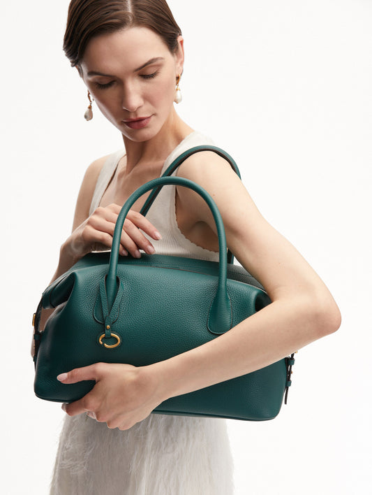 Model Holding the Dahlia Leather Handbag in Green with Detachable Shoulder Strap and O logo tag around the Top Handle. Front View