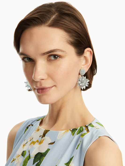 The model is wearing blue beaded flower earrings with raffia detailing. Front view.