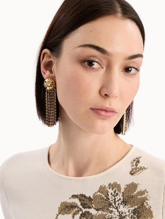 The model is wearing the Crystal Fringe Chandelier Earrings in Gold. Detail View.