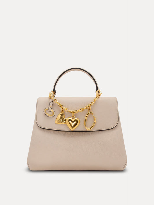 Heart & O Bag Charm in Gold styled with an ivory mini top handle handbag. Front View