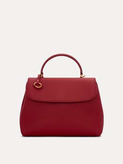 Model in plaid dress wearing The Poppy leather handbag in red with O logo around the top handle. Front View