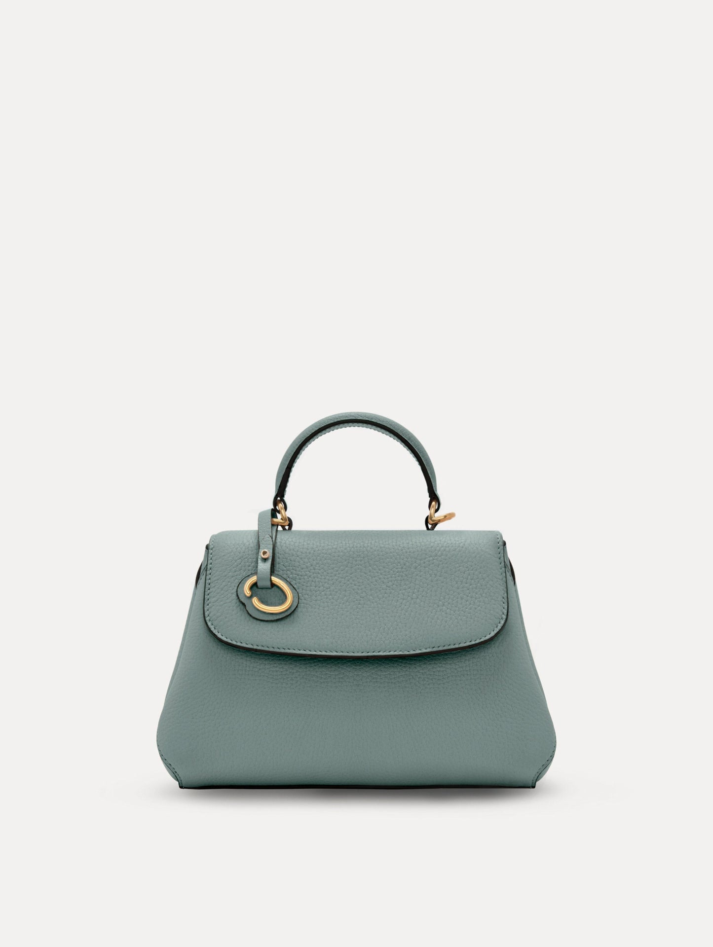 The Mini Poppy handbag in a Mint color with an Oscar O logo tag around the top handle, paired with a floral white dress. Front View.