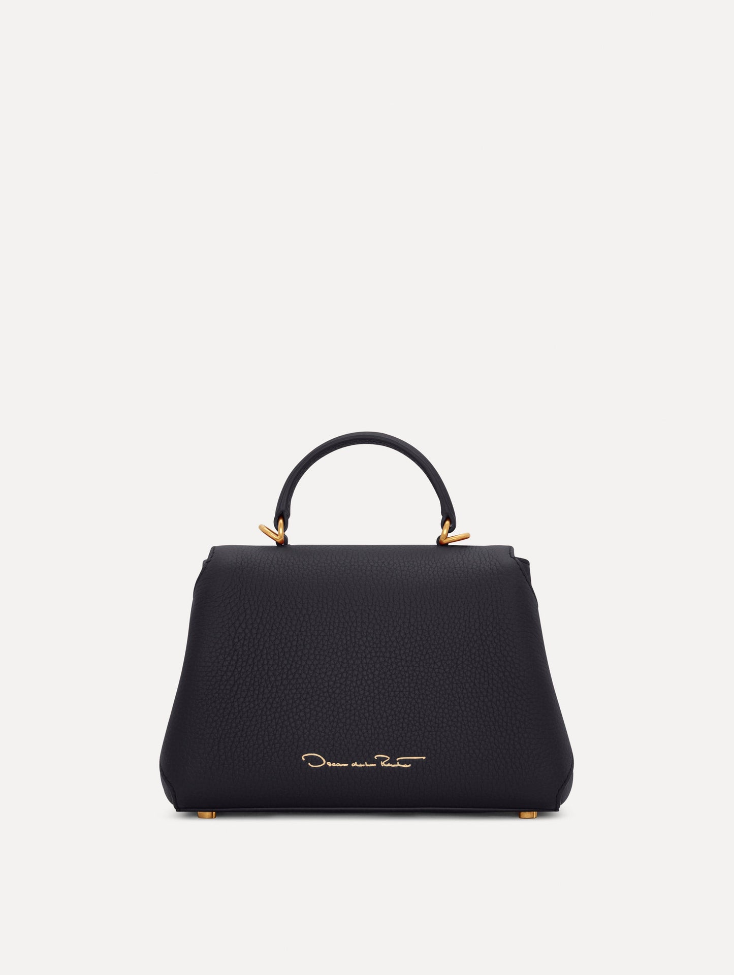 Mini Poppy in a light dark navy. The Mini Poppy is a top handle bag with a detachable shoulder strap, and it has the Oscar O logo attached around the top handle. Back View.