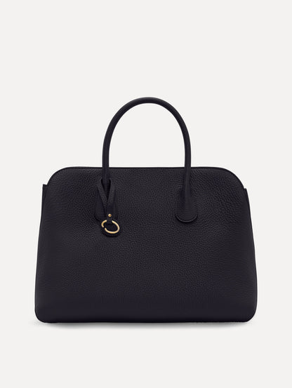 The Ivy top handle handbag in black, paired with some khaki pants. The bag comes with the Oscar O logo as a tag around the handle. Front View.