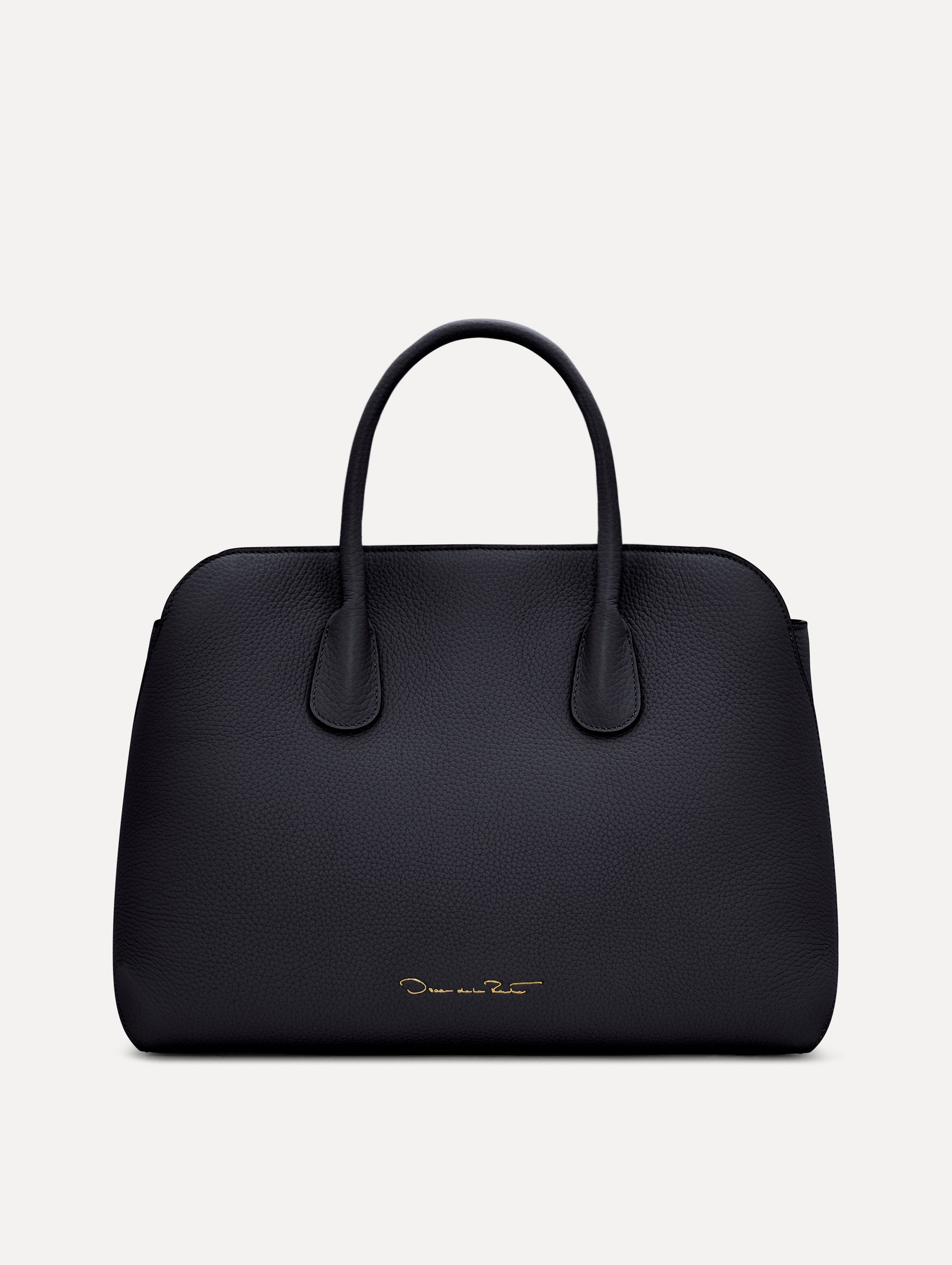 The Ivy top handle handbag in black, paired with some khaki pants. The bag comes with the Oscar O logo as a tag around the handle. Back View.