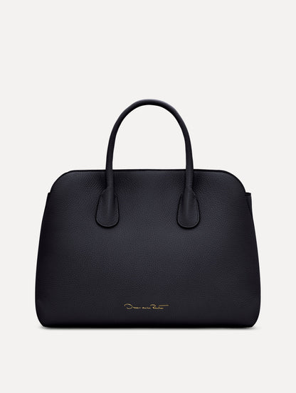 The Ivy top handle handbag in black, paired with some khaki pants. The bag comes with the Oscar O logo as a tag around the handle. Back View.
