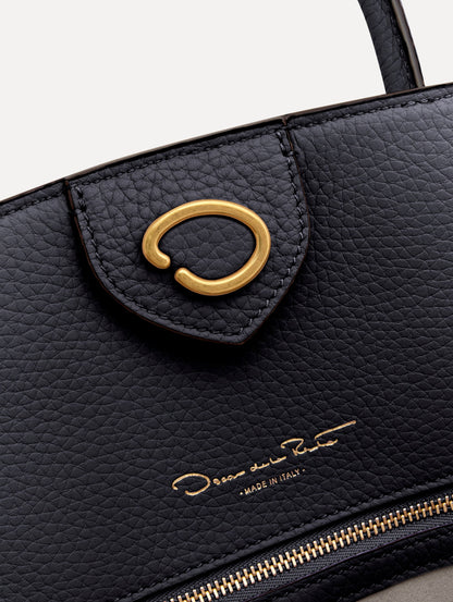 The Ivy top handle handbag in black, paired with some khaki pants. The bag comes with the Oscar O logo as a tag around the handle. Zoom View.