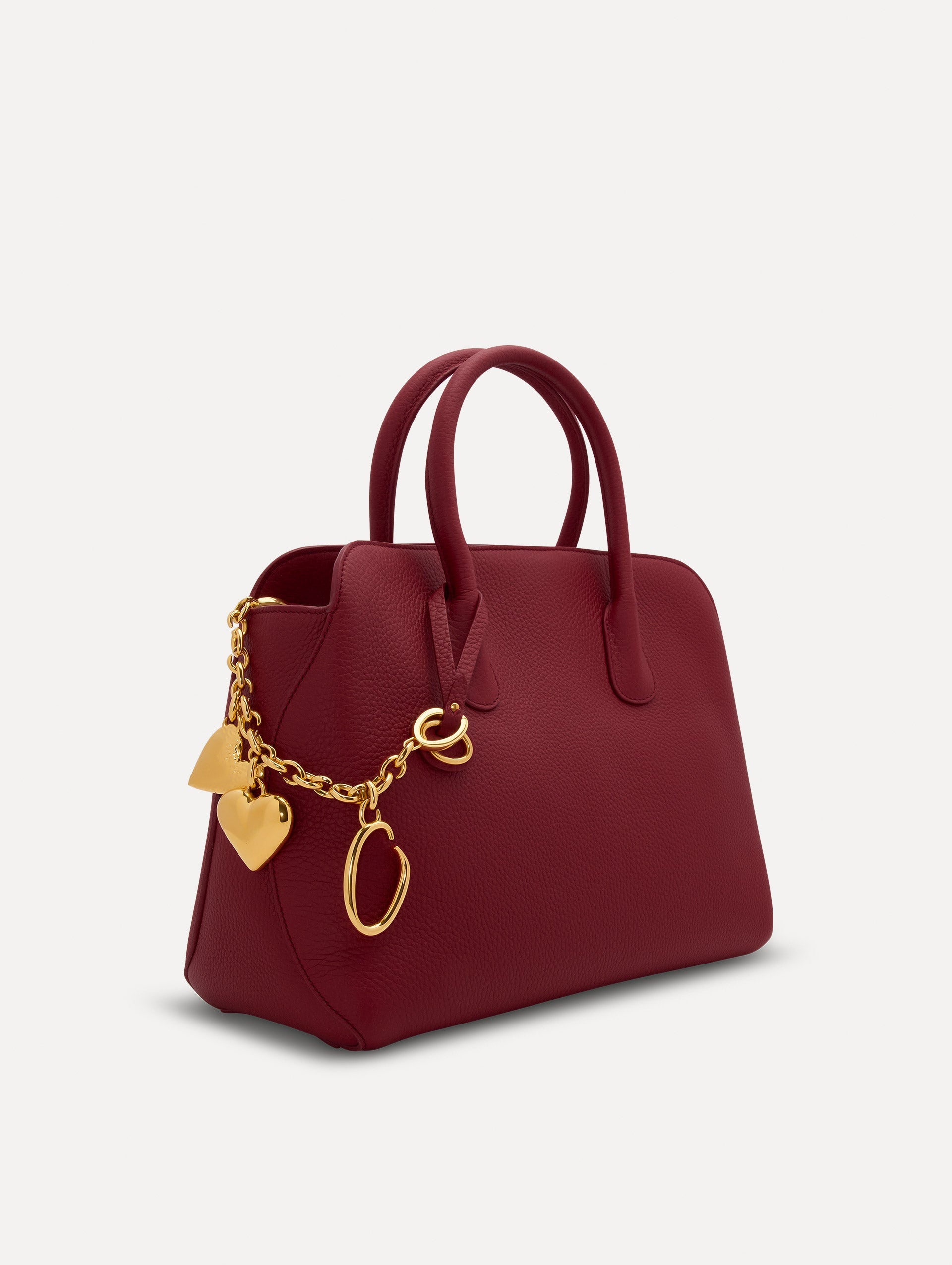 Heart & O Bag Charm in Gold styled with a red top handle handbag. Front View