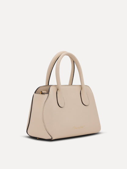 The Mini Ivy top handle handbag in Ivory. This bag comes with a detachable shoulder strap and has an Oscar O logo tag around the handle. Side View.