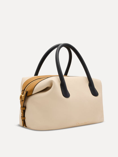 The Dahlia Handbag in Ivory with Black Top Handle and Honey sides. Adorned with Oscar de la Renta's signature logo in the bottom center of the back of the bag. Side View.