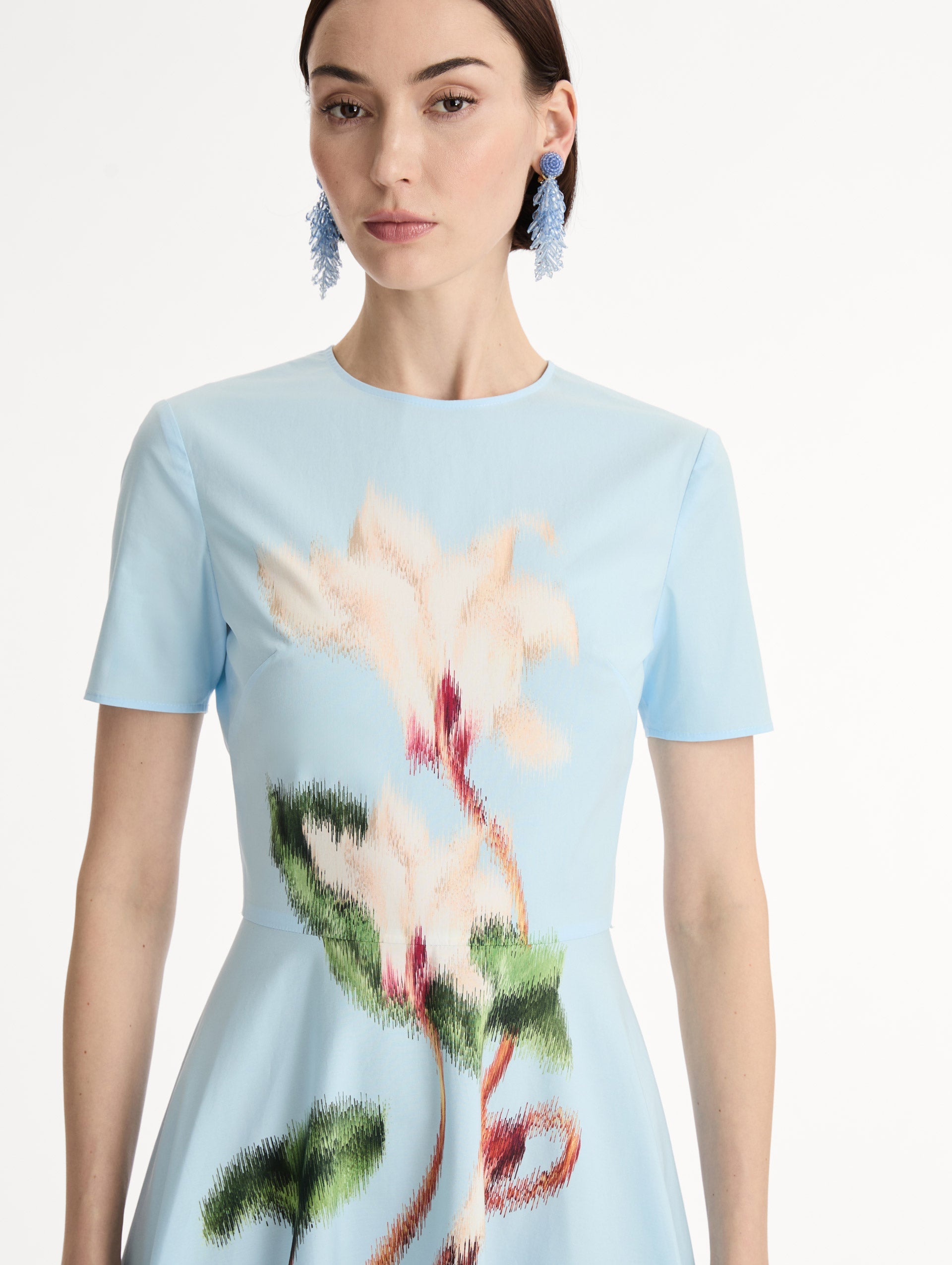 Short sleeve, light blue cotton poplin midi dress. Fitted bodice, full A-line skirt. Chiné Cyclamen motif with blurred, edges. Front View, Close Up.