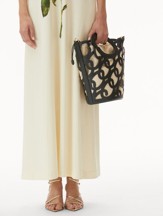 Model in white dress wearing Navy Oscar Chain-Link Leather Tote, formed by interlocking 'O' emblems and a large 'O' forms the top handle, with a removable interior pouch. Front View