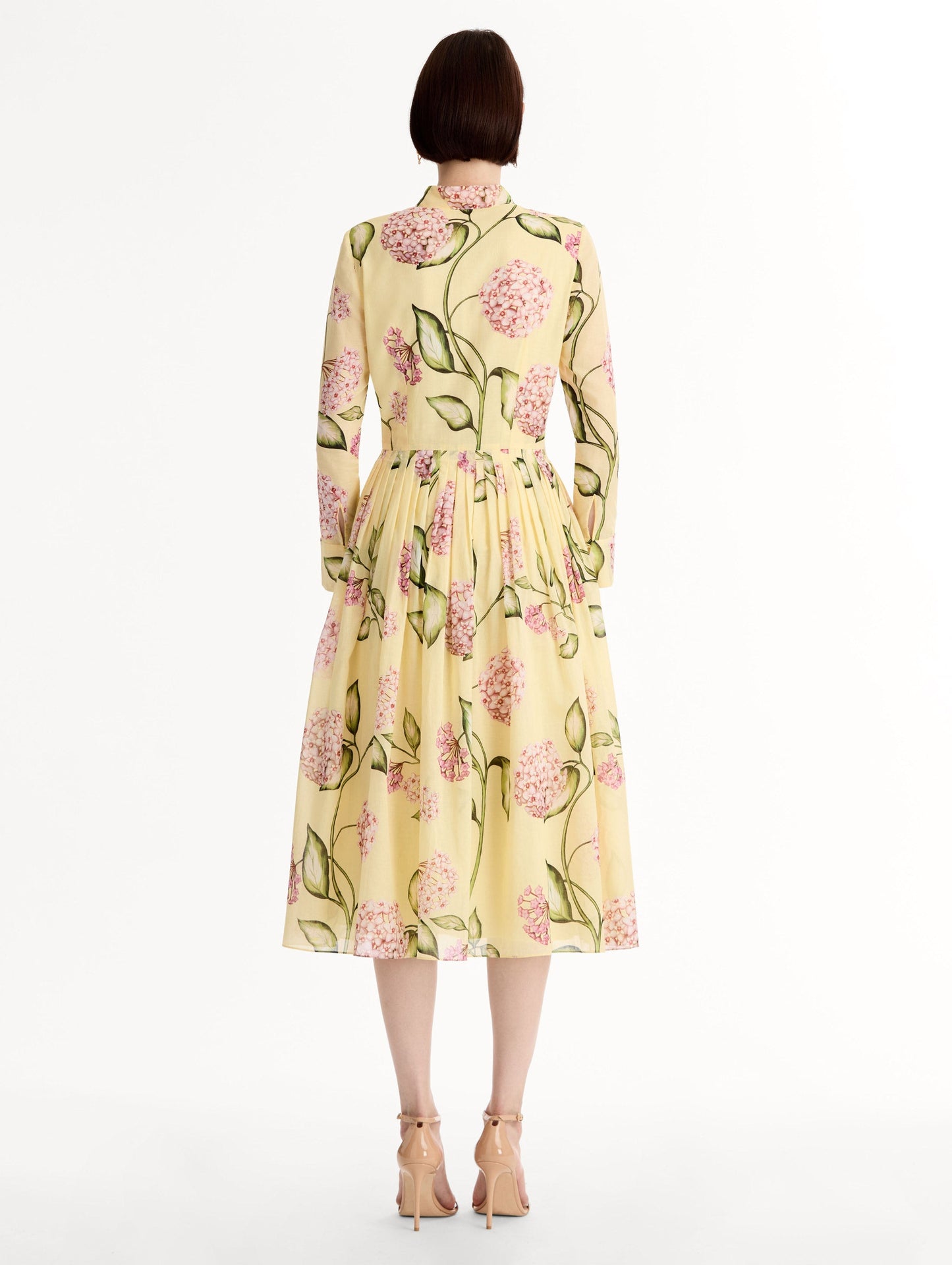 Long-sleeve, yellow cotton poplin midi dress. Porcelain flower print. Pleated silhouette. Concealed button front. Softly structured collar. Back View.