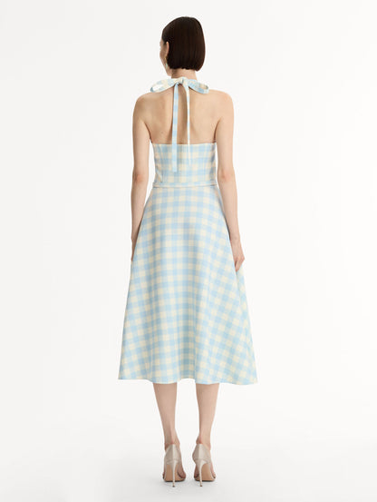 Pale blue and ivory gingham wool-blend halter dress. Structured bodice, flared midi skirt, and covered belt at the waist. Back View.