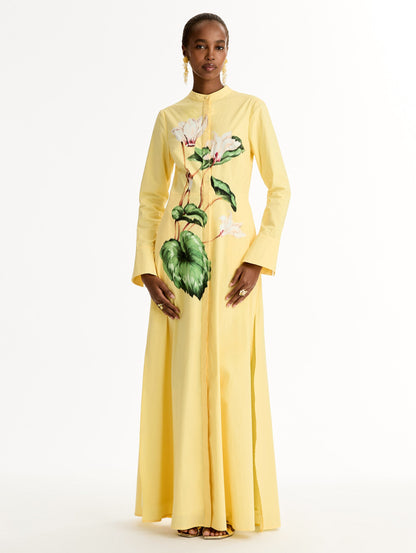 Yellow cotton poplin caftan with a mandarin collar and concealed button front. Chiné Cyclamen motif softly blurred, edges. Full-length sleeves. Front View.