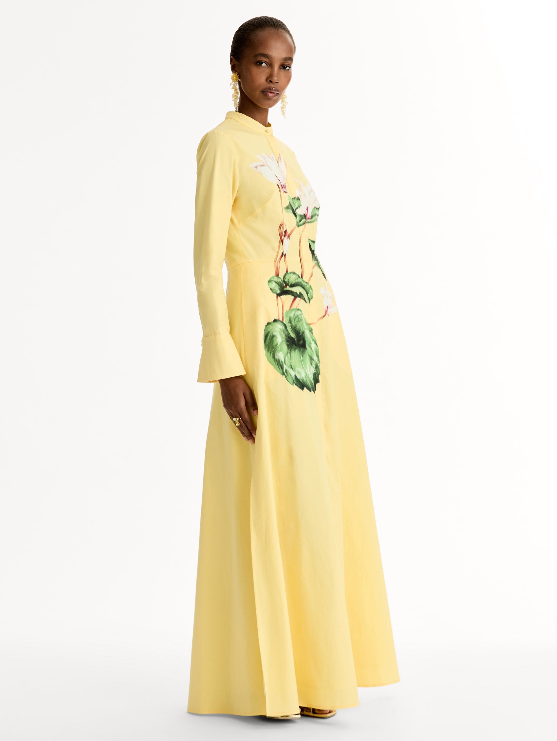 Yellow cotton poplin caftan with a mandarin collar and concealed button front. Chiné Cyclamen motif softly blurred, edges. Full-length sleeves. Side View.