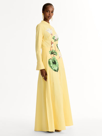 Yellow cotton poplin caftan with a mandarin collar and concealed button front. Chiné Cyclamen motif softly blurred, edges. Full-length sleeves. Side View.