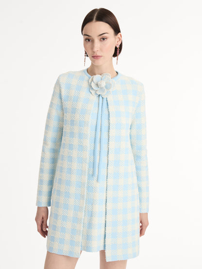 Textured jacquard, long sleeve coat in pale blue and ivory gingham pattern. Streamlined silhouette with a floral appliqué at the neckline. Front View, Close Up.