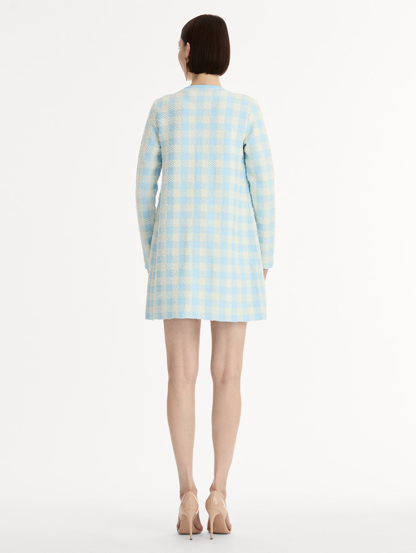 Textured jacquard, long sleeve coat in pale blue and ivory gingham pattern. Streamlined silhouette with a floral appliqué at the neckline. Back View.