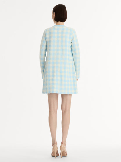 Textured jacquard, long sleeve coat in pale blue and ivory gingham pattern. Streamlined silhouette with a floral appliqué at the neckline. Back View.