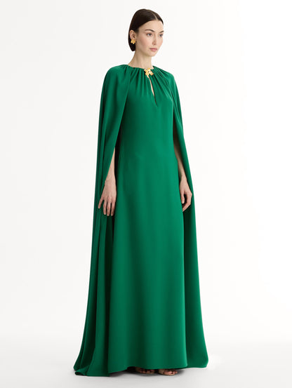 Emerald georgette caftan with fluid silhouette. Singular gilded cyclamen detail offers a sculptural focal point. Sweeping cape-like shape. Side View.