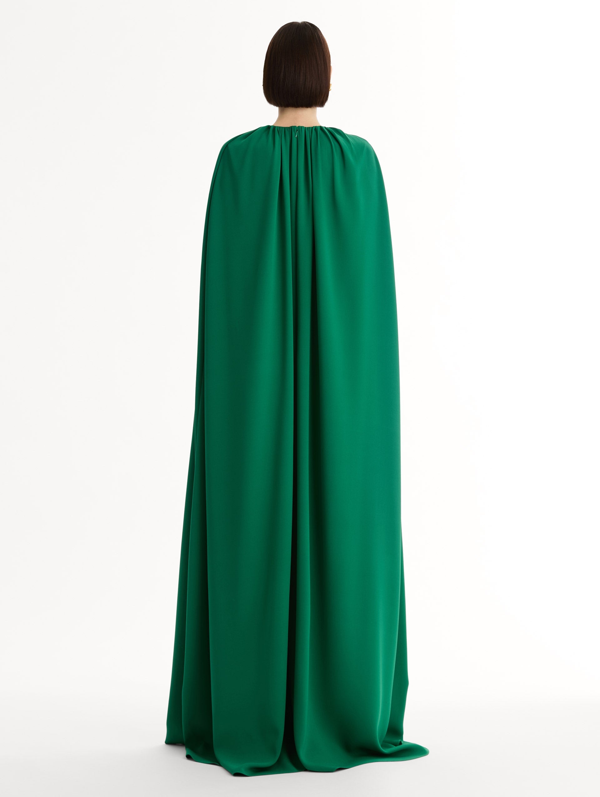 Emerald georgette caftan with fluid silhouette. Singular gilded cyclamen detail offers a sculptural focal point. Sweeping cape-like shape. back View.