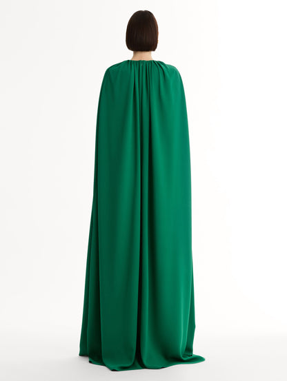 Emerald georgette caftan with fluid silhouette. Singular gilded cyclamen detail offers a sculptural focal point. Sweeping cape-like shape. back View.