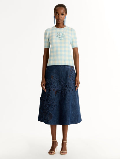 Short sleeve Knit pullover in classic pale blue and white gingham wool. Dimensional floral appliqué at the neckline. Front View.