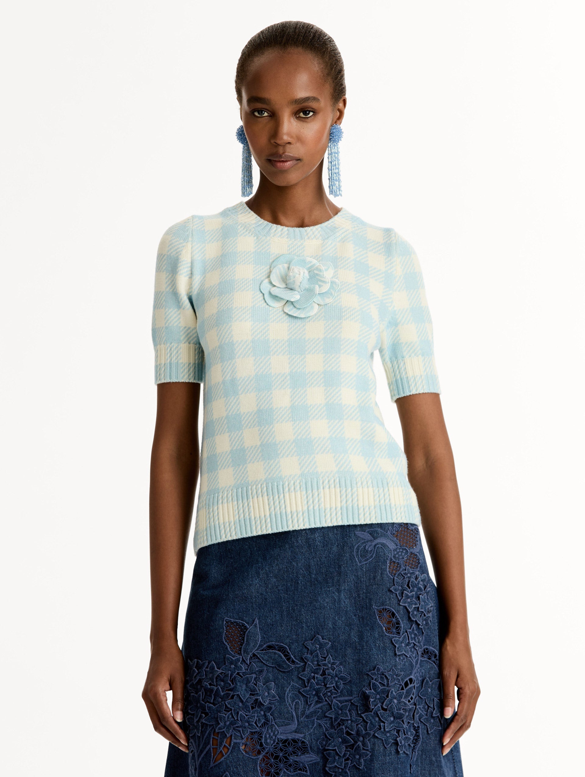 Short sleeve Knit pullover in classic pale blue and white gingham wool. Dimensional floral appliqué at the neckline. Front View.