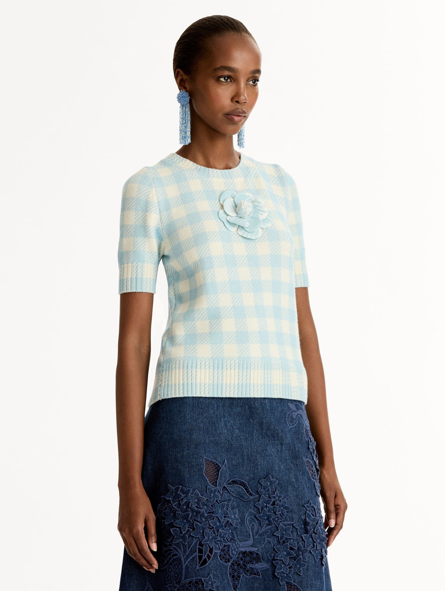 Short sleeve Knit pullover in classic pale blue and white gingham wool. Dimensional floral appliqué at the neckline. Side View.