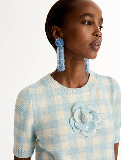 Short sleeve Knit pullover in classic pale blue and white gingham wool. Dimensional floral appliqué at the neckline. Front View.