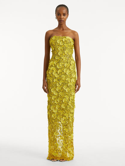 Full body front view of model wearing a yellow gown with peony raffia and sequin embroidery. With a strapless neckline and column silhouette.