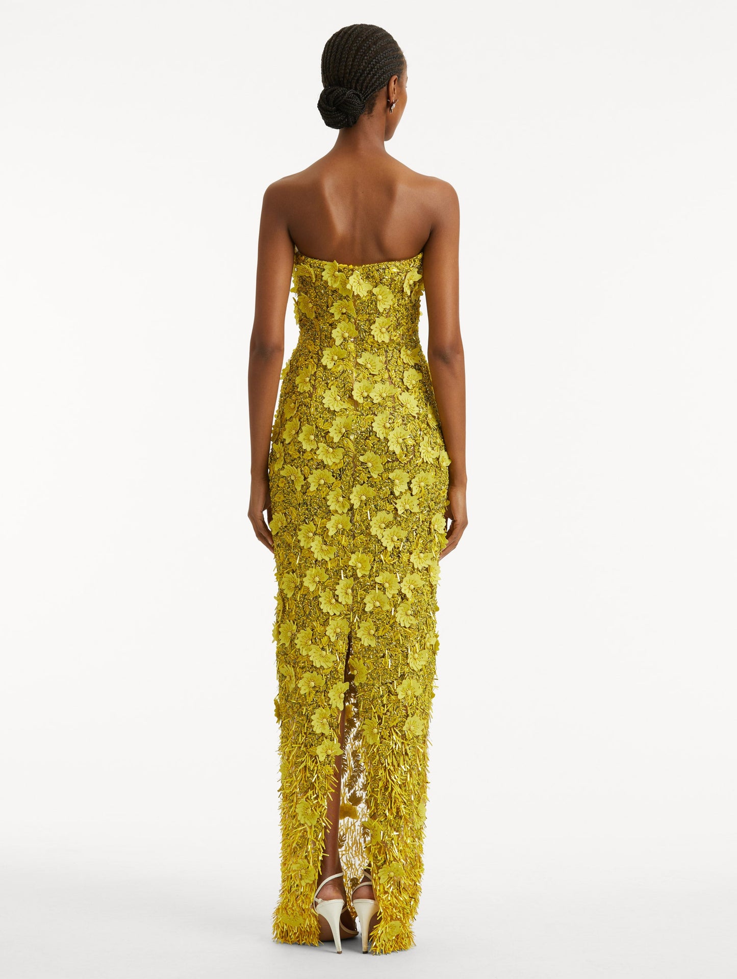 Full body back view of model wearing a yellow gown with peony raffia and sequin embroidery. With a strapless column silhouette and center back slit.