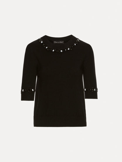 Short sleeve black pullover with a crew neckline and intricate sequin embroidery of ivory and noir florets which trace the trim